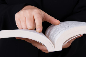 Young business woman in dark suit reading book and pointing line.